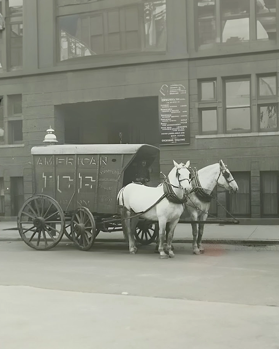 Two horses pulling a carriage down the street.