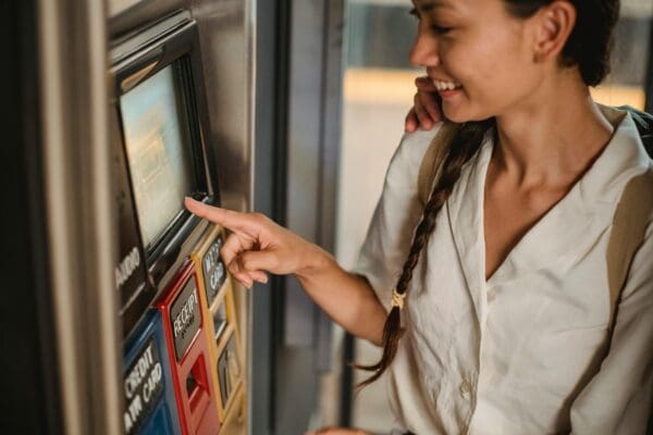 A woman is pointing to the screen on an atm machine.