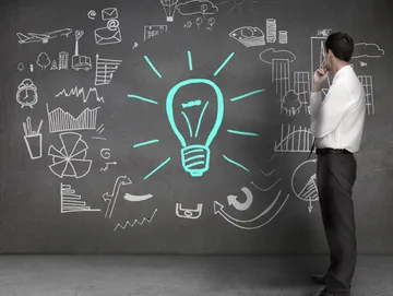 A man standing in front of a chalkboard with a light bulb drawn on it.